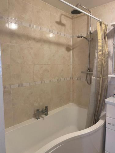 a bathroom with a bath tub and a sink at Hameway House- Stunning 4 bedroom house with a spacious kitchen in London