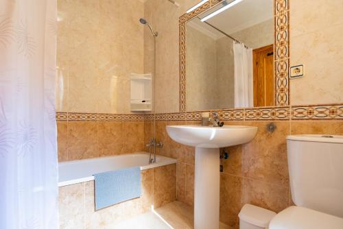 een badkamer met een wastafel, een toilet en een spiegel bij Casa Gris in Orihuela