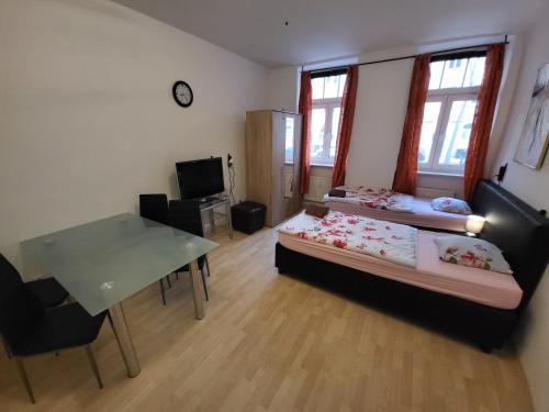 a room with two beds and a table and a desk at Apartmentzimmer in Erfurt