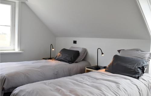 two beds in a white room with two lamps at 4 Bedroom Awesome Home In Langemark in Langemark
