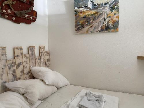 un lit avec deux oreillers et un tableau au mur dans l'établissement Appartement 1 pièce 35m² - Centre Étel - Vue port - 3 pers. - FR-1-397-51, à Étel