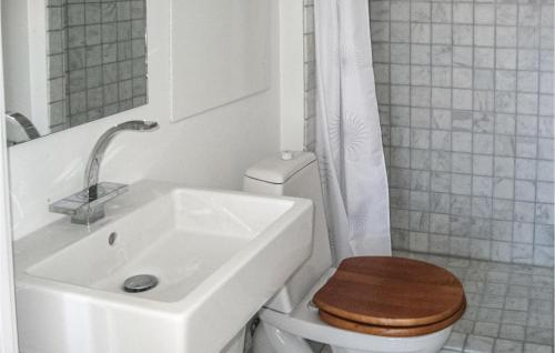a bathroom with a sink and a toilet with a wooden seat at Beautiful Apartment In Gudhjem With 1 Bedrooms, Wifi And Outdoor Swimming Pool in Gudhjem