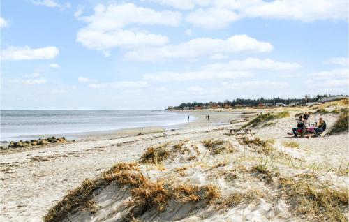 a beach with people sitting on benches on the sand at 6 Bedroom Nice Home In Glesborg in Glesborg