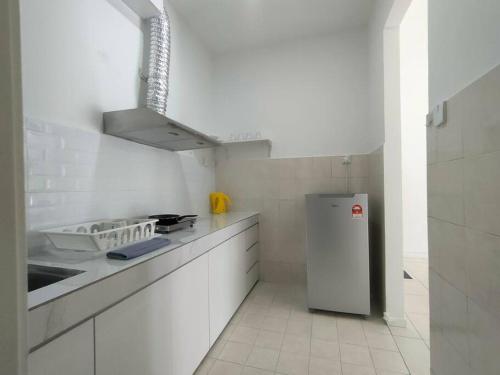 La cuisine blanche est équipée d'un réfrigérateur et d'un évier. dans l'établissement The Baiduri Courts, à Puchong