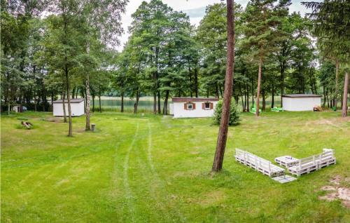 two benches sitting in a field with trees at Cozy Home In Sulnowo With Kitchen in Sulnówko