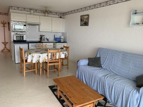 un salon avec un canapé bleu et une table dans l'établissement Fort-Mahon-Plage: Appartement proche plage avec garage - FR-1-482-111, à Fort-Mahon-Plage