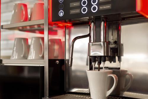 a coffee maker with a white cup in a kitchen at Citadines Michel Hamburg in Hamburg