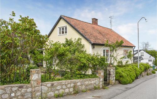 a white house with a stone wall next to a street at Stunning Home In Simrishamn With Wifi in Simrishamn