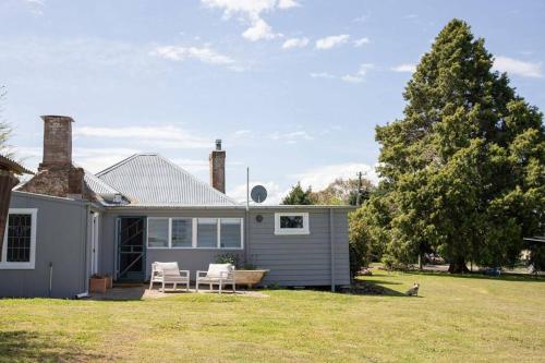 a house with two chairs and a table in the yard at Woolbrook Cottage - Charming 1890's Heritage in Taralga
