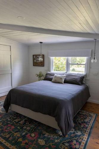 a bedroom with a large bed in front of a window at Woolbrook Cottage - Charming 1890's Heritage in Taralga