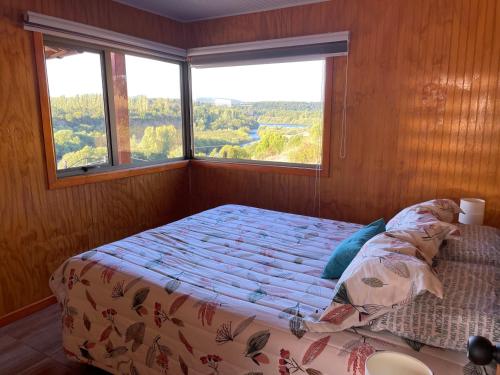 a bed in a room with a large window at Cabañas Trialye in Quilaco