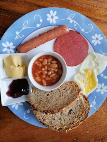Un plato de comida para el desayuno con salchichas, frijoles, frijoles y pan. en La Bella Swiss Inn, en San Vicente