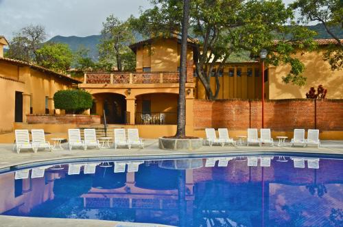 a swimming pool with white chairs and a house at Villas Danza del Sol in Ajijic