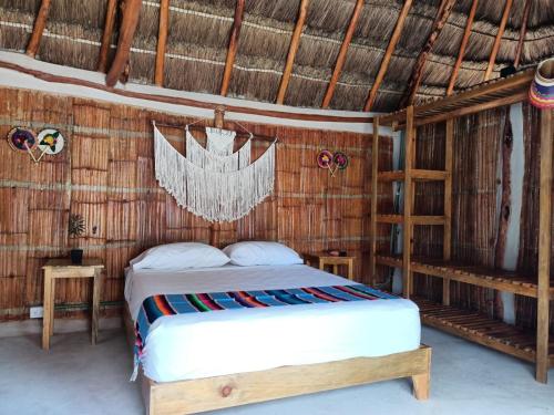 a bedroom with a bed in a straw hut at Cabañas Cinco Elementos in Celestún