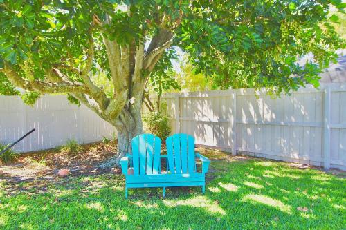 two blue chairs sitting next to a tree in a yard at Sandpiper Stay in Port Saint Lucie