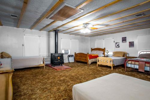 3H Ranch Mountain Retreat في Medina: غرفة بها عدة أسرة وموقد خشبي