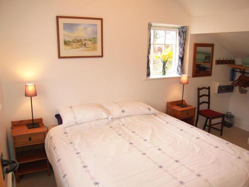 a bedroom with a bed and two lamps and a window at Sycamore Cottage in Ellonby