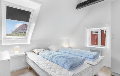 a white room with a bed with blue pillows on it at Amazing Apartment In Gudhjem With 2 Bedrooms, Wifi And Outdoor Swimming Pool in Gudhjem
