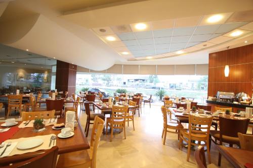 a restaurant with wooden tables and chairs and a large window at Hotel Mercury Inn in Querétaro