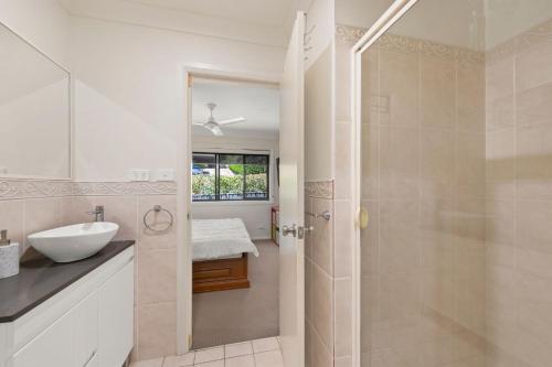 une salle de bain blanche avec lavabo et douche dans l'établissement Trumpeter, à Corlette