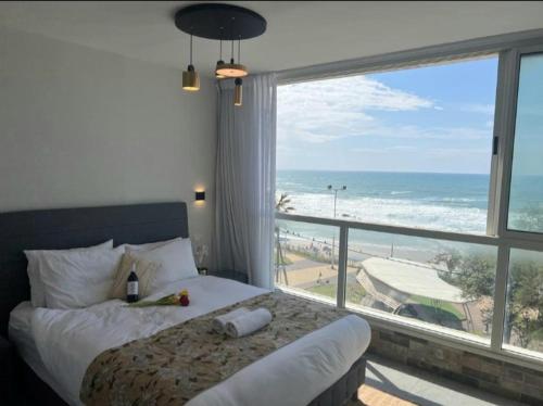 a bedroom with a bed and a view of the ocean at sea view apartment in Bat Yam