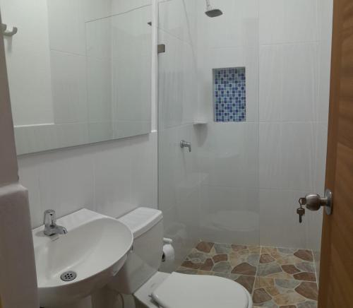 y baño con aseo, lavabo y ducha. en Hotel Santa Fe del Parque en Santa Fe de Antioquia