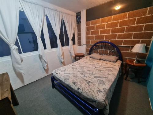 a bedroom with a bed and a brick wall at HOSTAL DEL ELEFANTE in Tepoztlán