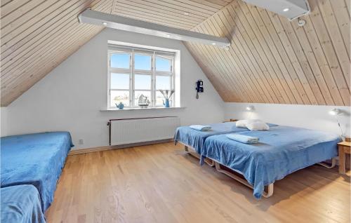 a attic bedroom with two beds and a window at 1 Bedroom Pet Friendly Apartment In Nrre Alslev in Nørre Alslev