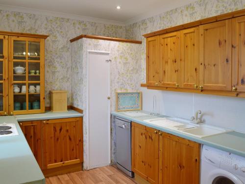 a kitchen with wooden cabinets and a dishwasher at Mercy Cottage - Beaufort Estate in Belladrum