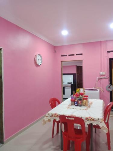 ein Esszimmer mit rosa Wänden und einem Tisch mit roten Stühlen in der Unterkunft Kuntum Cottage Bad & Breakfast in Kampong Tanjong Ipoh