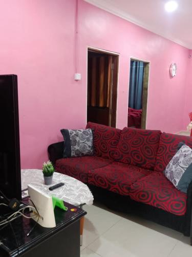 ein Wohnzimmer mit einem roten Sofa und einem Schreibtisch mit einem Computer in der Unterkunft Kuntum Cottage Bad & Breakfast in Kampong Tanjong Ipoh