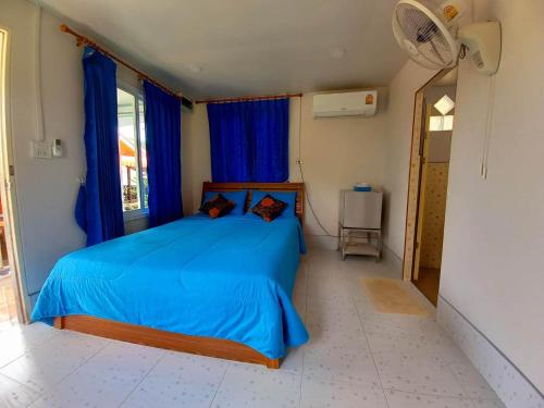 a bedroom with a bed with blue sheets and a fan at Patcharin Homestay in Ban Lo Pla Lai (1)