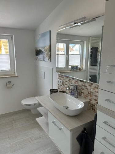 a white bathroom with a sink and a toilet at Timeless - die Ferienwohnung in Wasserburg in Bettnau