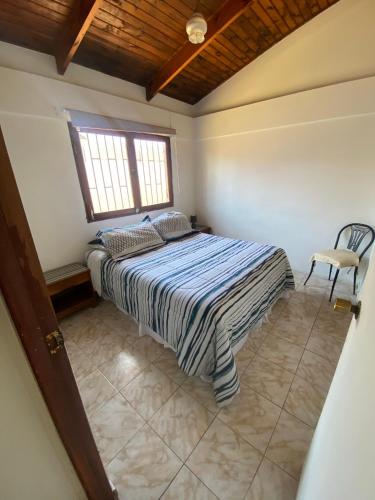 a bedroom with a bed and a window and a chair at Cabaña a pasos del Faro De La Serena in La Serena