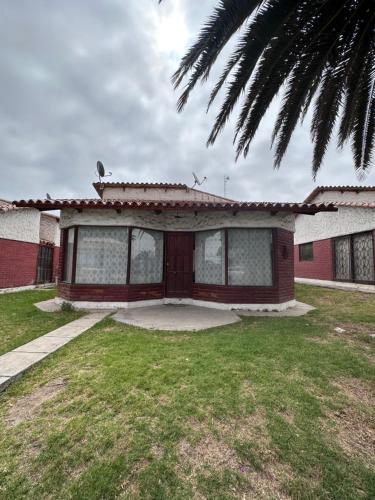 a house with a palm tree in front of it at Cabaña a pasos del Faro De La Serena in La Serena