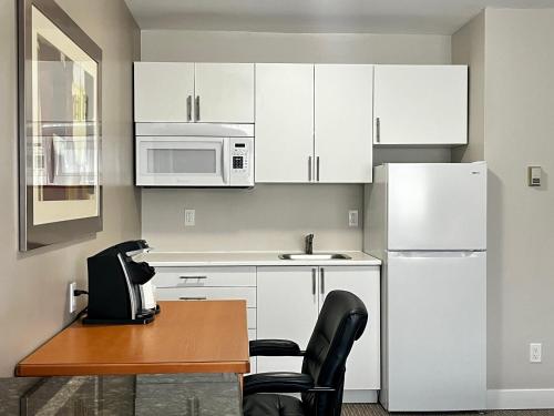 a kitchen with white cabinets and a table and a refrigerator at Anavada Inn & Suites - Prince George in Prince George