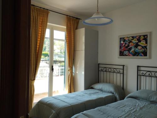 a bedroom with two beds and a window with a door at Villa Amelie (Mare e Relax) in Bisceglie