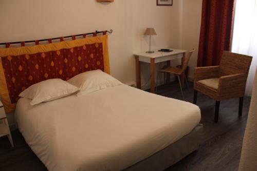 a bedroom with a bed and a chair and a table at Hotel d'Angleterre in Avignon