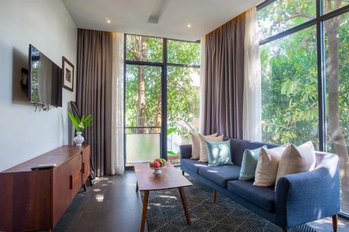 a living room with a blue couch and large windows at Maison Leab in Siem Reap