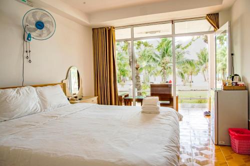 a bedroom with a white bed and a large window at Thiên Tân Hotel in Con Dao