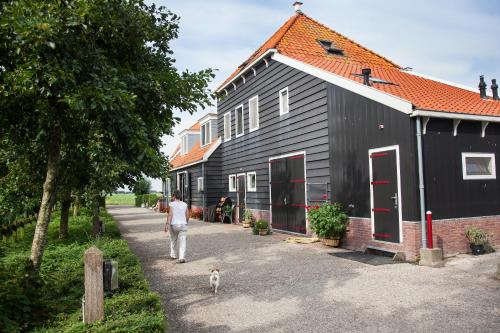 a man walking a dog in front of a black house at Farm Overleekerhoeve in Monnickendam