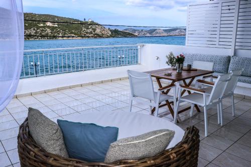 a balcony with a table and chairs and a view of the water at Grand Bleu Apartments & Villas in Ermioni