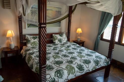 a bedroom with a canopy bed with a green and white comforter at Rischland Villas in Watamu