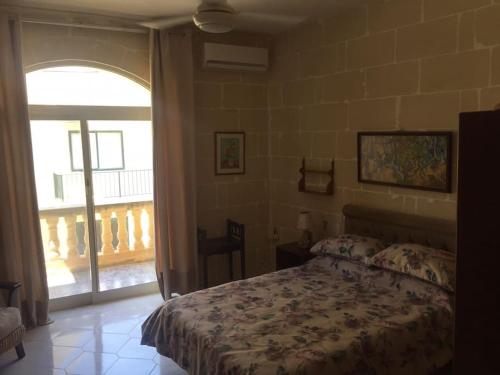 um quarto com uma cama e uma grande janela em Entire apartment with Ramla Bay view (Gozo, Malta) em Il-Pergla