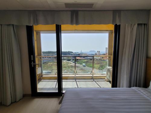 a bedroom with a bed and a large window at BK Hotel Jeju in Seogwipo