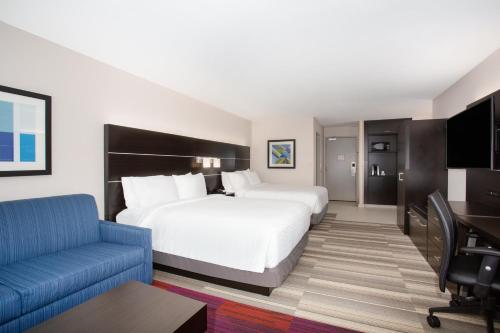 a hotel room with a large bed and a blue couch at Holiday Inn Express & Suites Lincoln City by IHG in Lincoln City