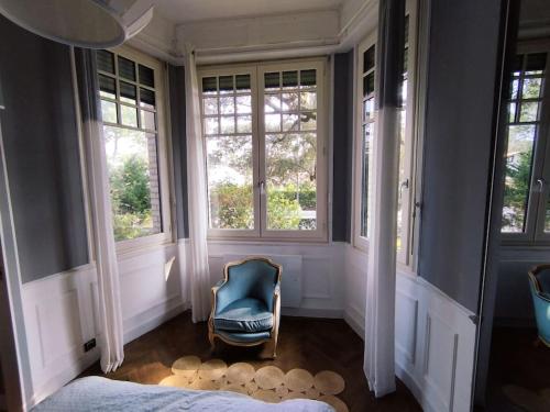a bedroom with a blue chair and windows at Le Moulleau Appartement 2 chambres - plage à 50m in La Teste-de-Buch