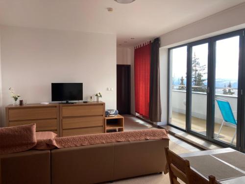 Apartman 106 Panorama Resort Štrbské Pleso في ستربشكي بليسو: غرفة معيشة مع أريكة ونافذة كبيرة