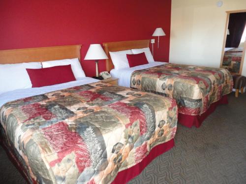 two beds in a hotel room with red walls at Sahara Courtyard Inn Penticton in Penticton