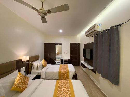 een hotelkamer met 2 bedden en een flatscreen-tv bij Le Shiv Executive Suite in Theni